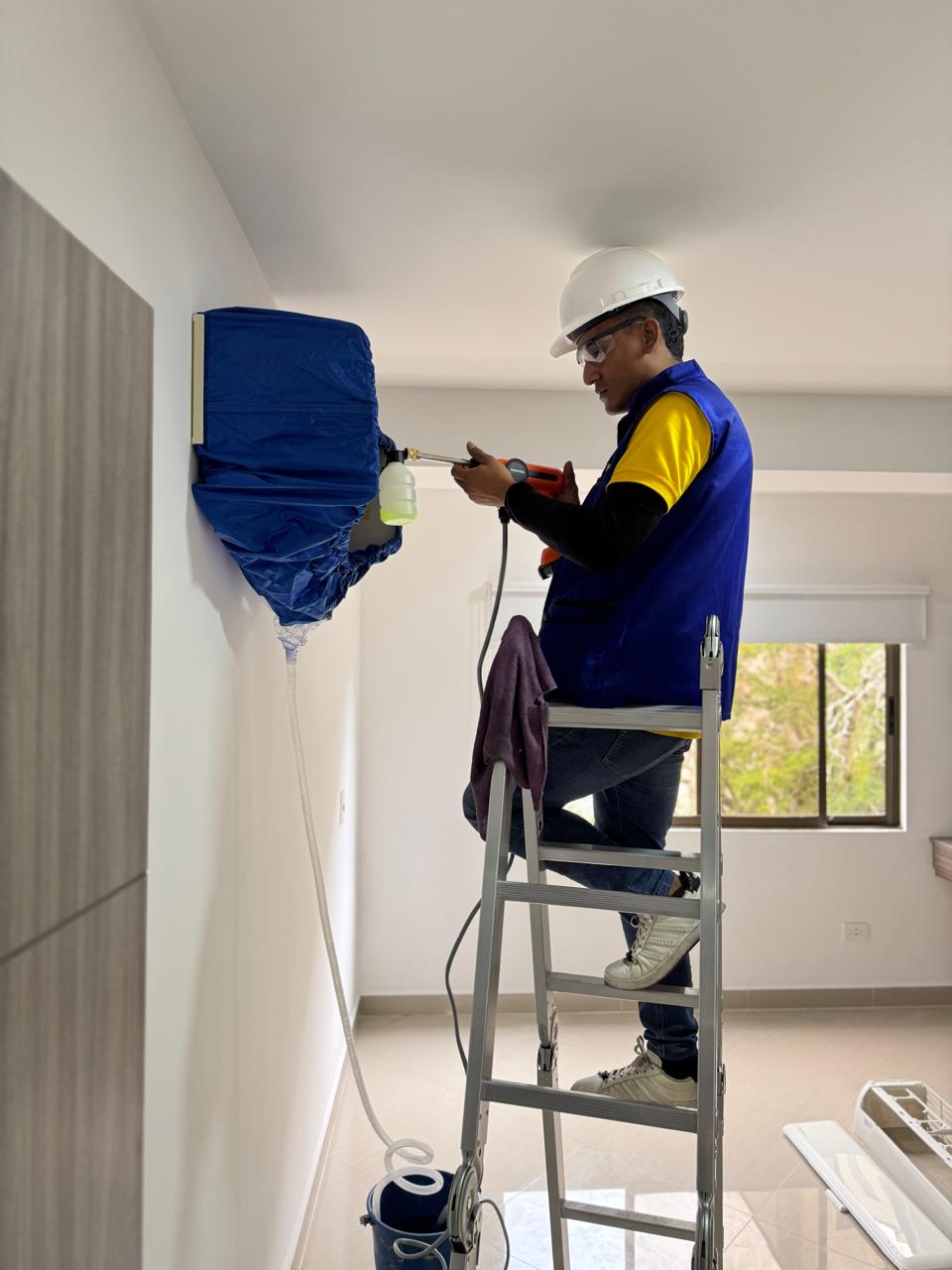 Técnico de Frío King con gafas de seguridad realizando limpieza de un aire acondicionado